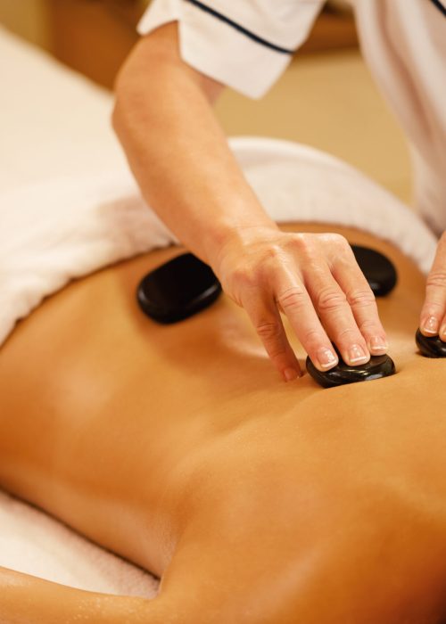 Unrecognizable woman relaxing during lastone therapy at wellness spa.