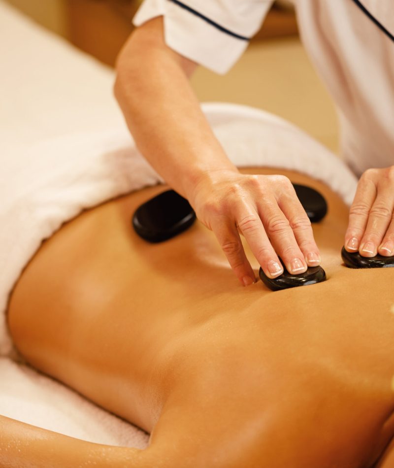 Unrecognizable woman relaxing during lastone therapy at wellness spa.