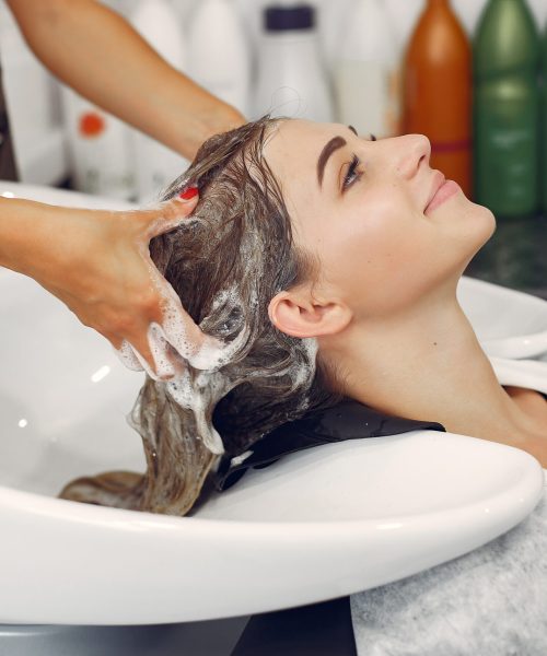 Hairdresser washing head her client. Woman in a hair salon